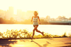 female runner running at sunset in city park. Healthy fitness woman jogging outdoors. Montreal skyline in background.
