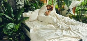 woman sleeping on Brentwood Home Non-toxic Mattress in verdant setting - photo