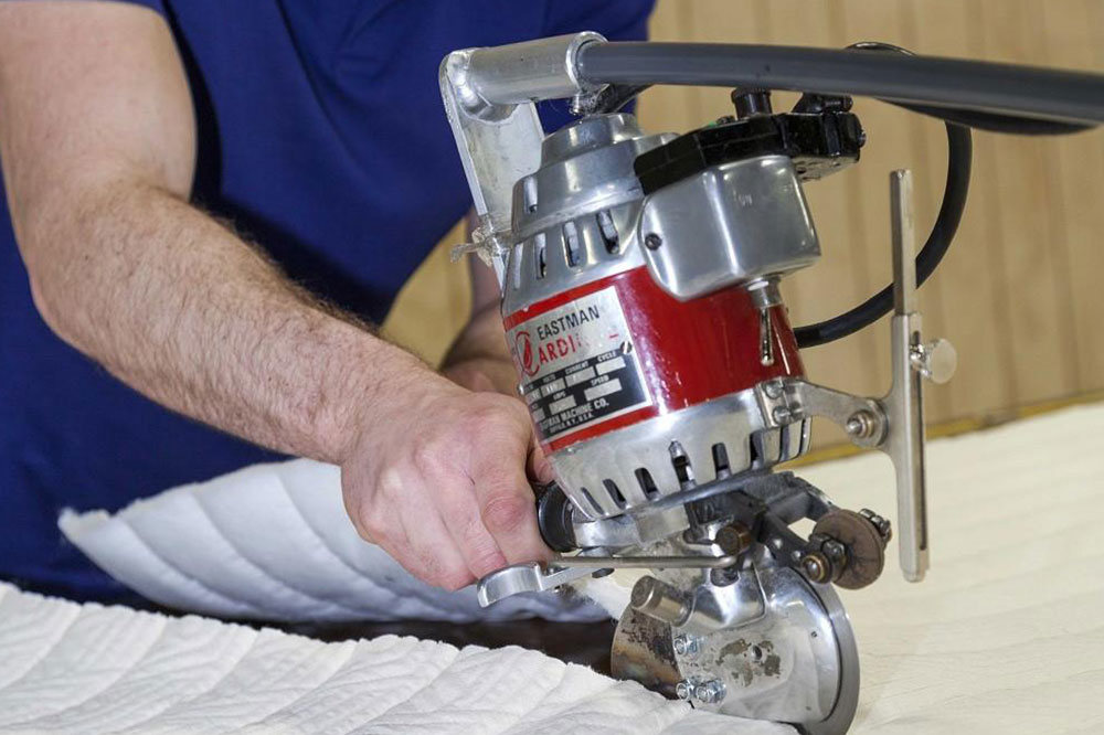 Close up view of man's arm using a machine to cut padding material