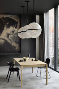 Viesso Ethnicraft Bok Oak Extendable Dining Table in diningroom with dark interior finishes; window, oversize pendant lights and artwork surround - photo
