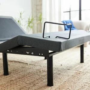 Adjustable bed base with gray fabric and black metal stands on beige carpet in airy room - photo