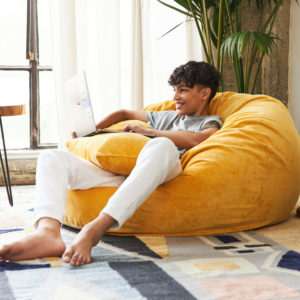 Young man enjoying Brentwood Home REPREVE bean bag lounger on yellow - photo
