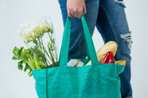 Mid section of woman carrying grocery bag against white background, reusable shopping bag, sustainable kitchen