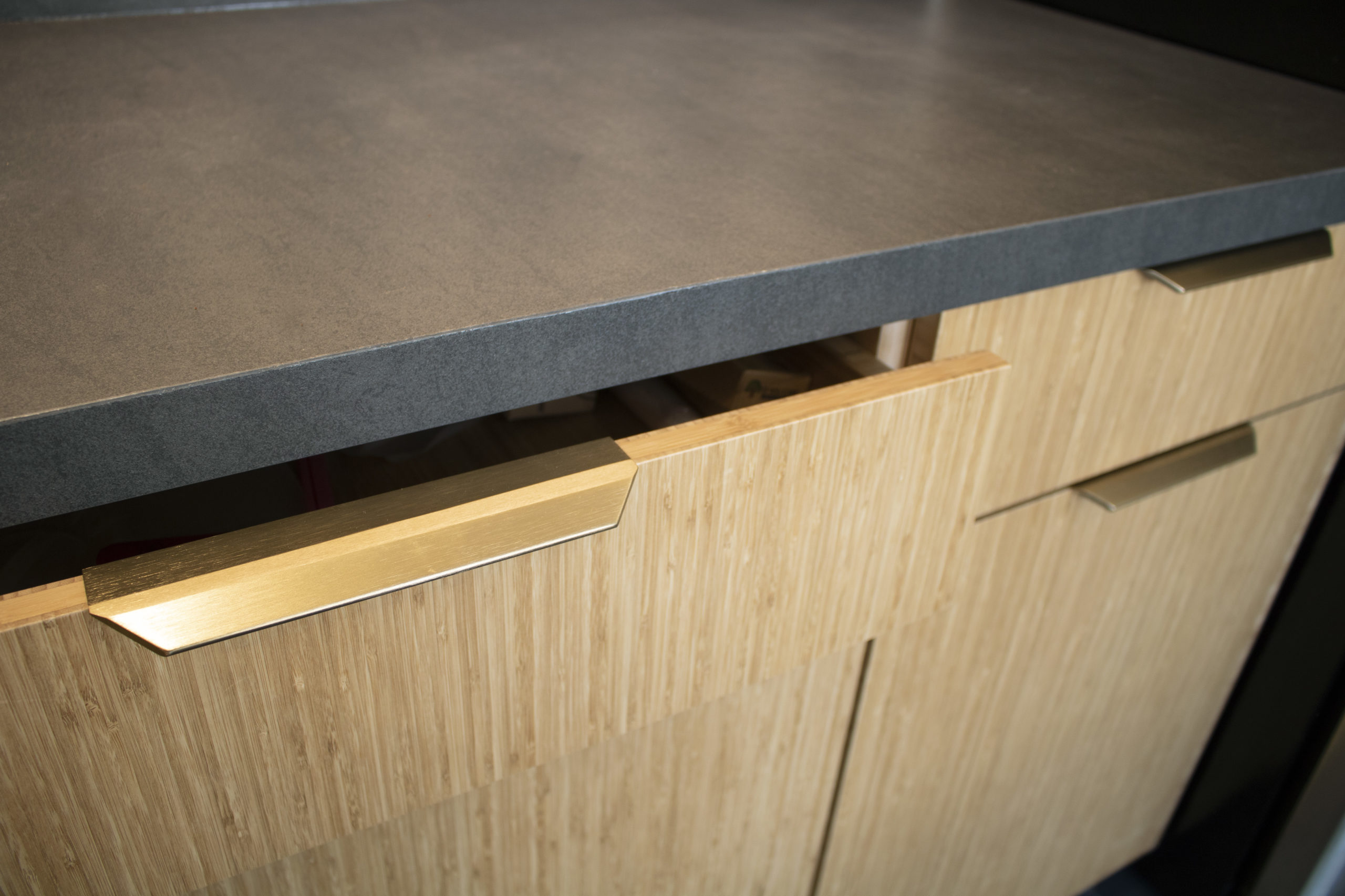 Up-close detail of open drawer and gold hardware, #EcoRenovate French Cabinetry Plyboo Cabinets and Dekton by Cosentino Countertop