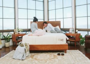couple converses in bedroom with large windows and organic mattresses by Nest