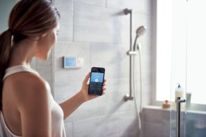 Woman with phone prepares hersmart shower