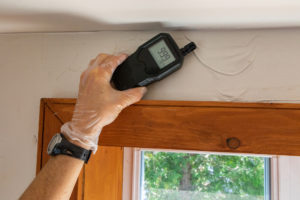 A close up view of an indoor environmental quality assessor using a handheld digital device with lcd numeric display during a residential dwelling check up.