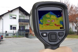 Handheld infrared scanner shows heat leaks from residence