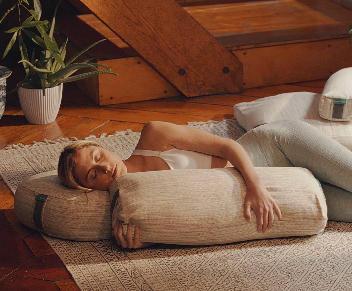 Woman in workout clothes rests, supported by natural yoga pillows