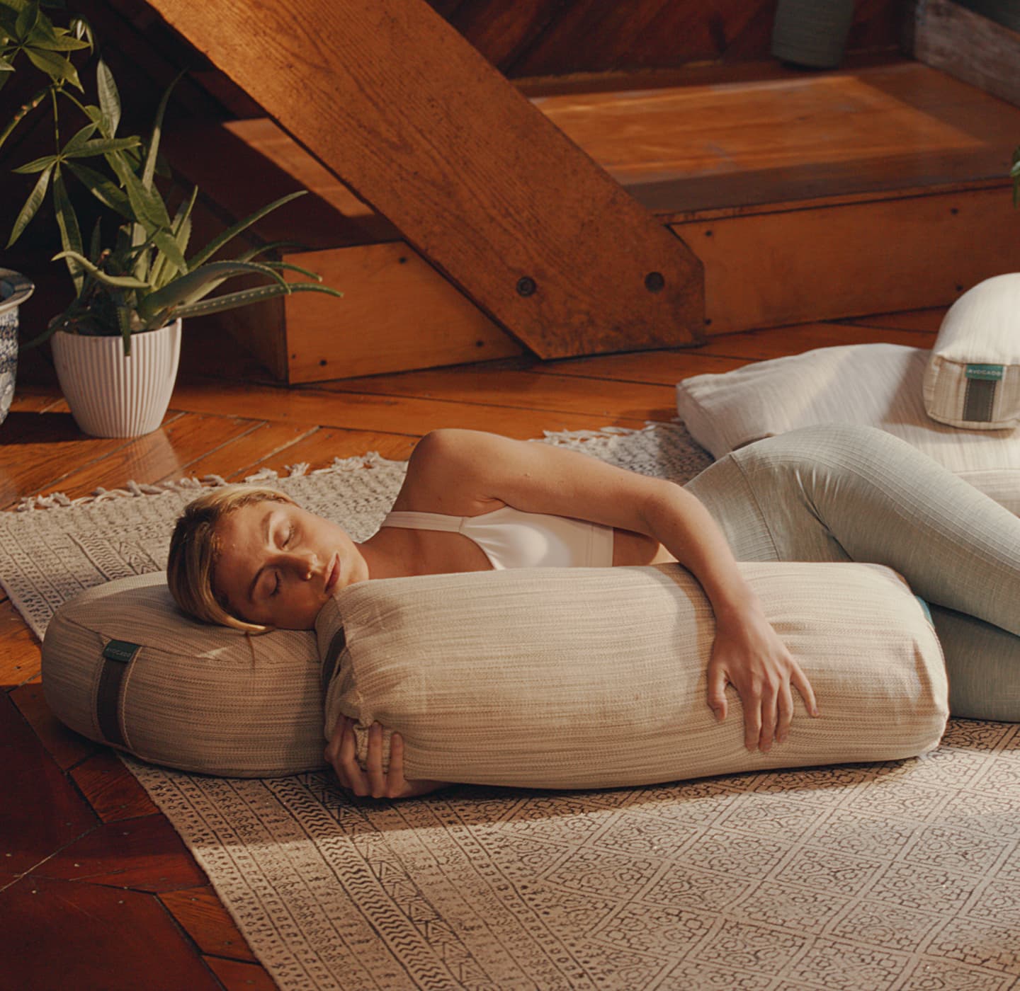 Woman in workout clothes rests, supported by natural yoga pillows