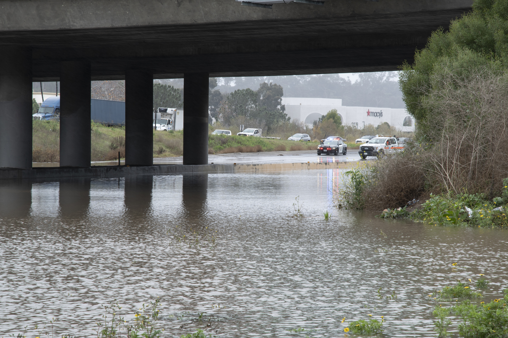 police block traffic near a freeway underpass due to  stormwater flooding - photo