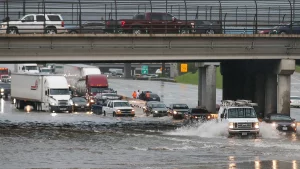 cars and trucks backed up a freeway underpass due to flooding; some cars making their way through high water