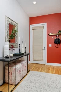 Entryway with red accent wall, botalnical artwork, wood floor and straw shade