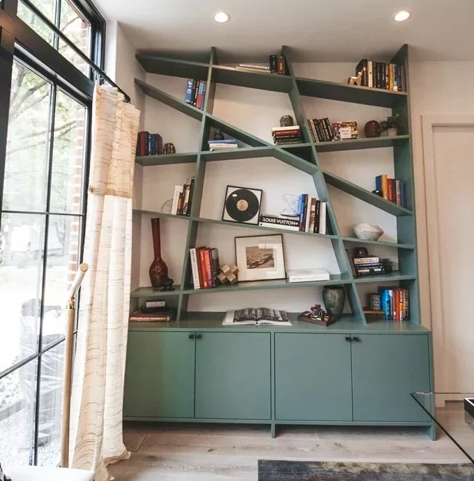 creative built-in bookcase painted green in white room iwith window and mottled brown rug