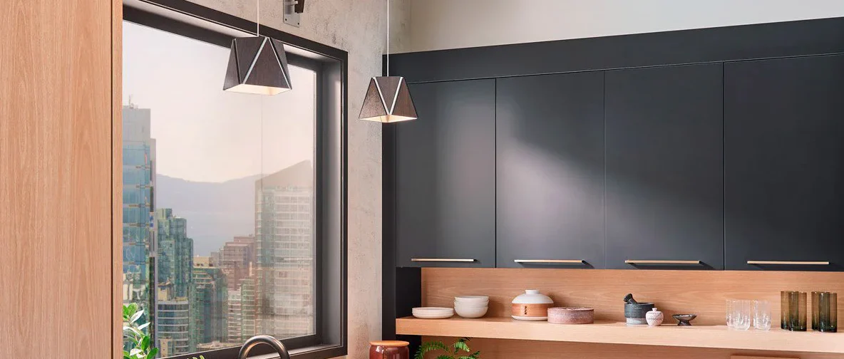 Sunny kitchen window looks out over cityscape; Calx pendants from Cerno ar sourrounded by dark cabinetry and light-wood built-ins - photo