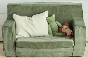 Squat play chair in eco-friendly green fabric; small pillow and stuffed toys on seat - photo