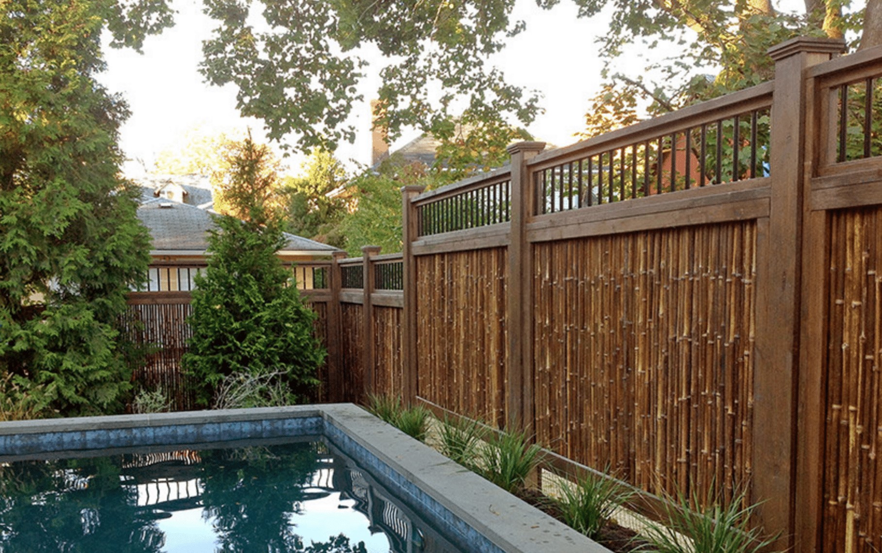 Dark brown fencing along a pool with landscaping
