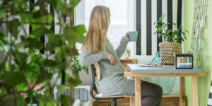 Young woman drinking coffee in green home office