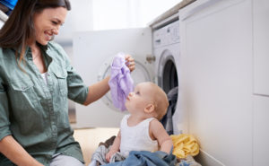 Shot of a mother and baby playing while doing laundry.