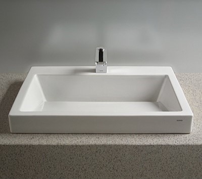White rectangular bathroom sink set into tan specked counter