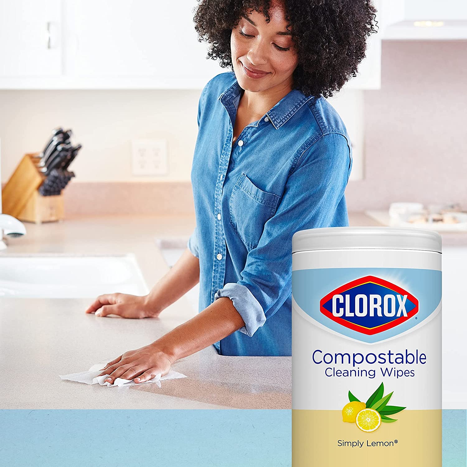 Smiling Woman of Color cleans kitchen counter  with wipe; inset image of Clorox composable wipes.