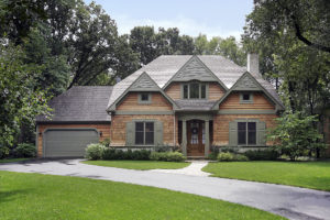Exterior view of home with gables; wood siding; interesting gray trim; walkway, curved drive, and green lawn in foreground
