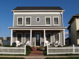 New two story vinyl home built to look like an old historical house with gray vinyl siding and large front porch.