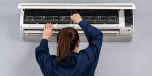 Female technician service using screwdriver to repairing the air conditioner indoors — Photo