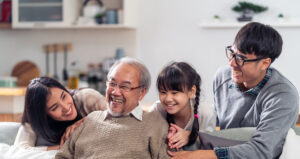 Group Portrait of Happy Multigenerational Asian family sit on sofa couch in living room with smile. Mutigenerational living concept.