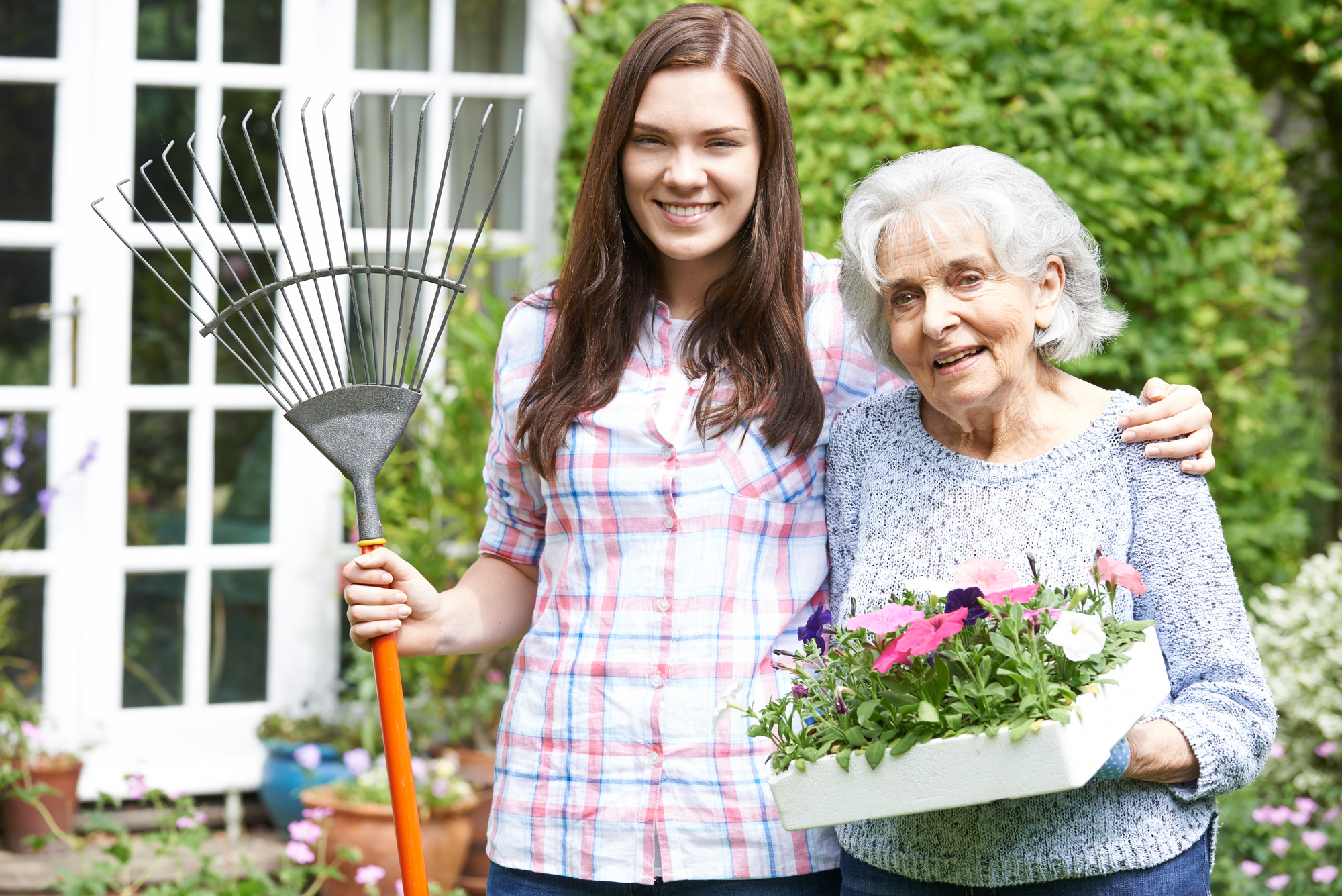Teenage Granddaughter Helping Grandmother In Garden; intergenerational - photo