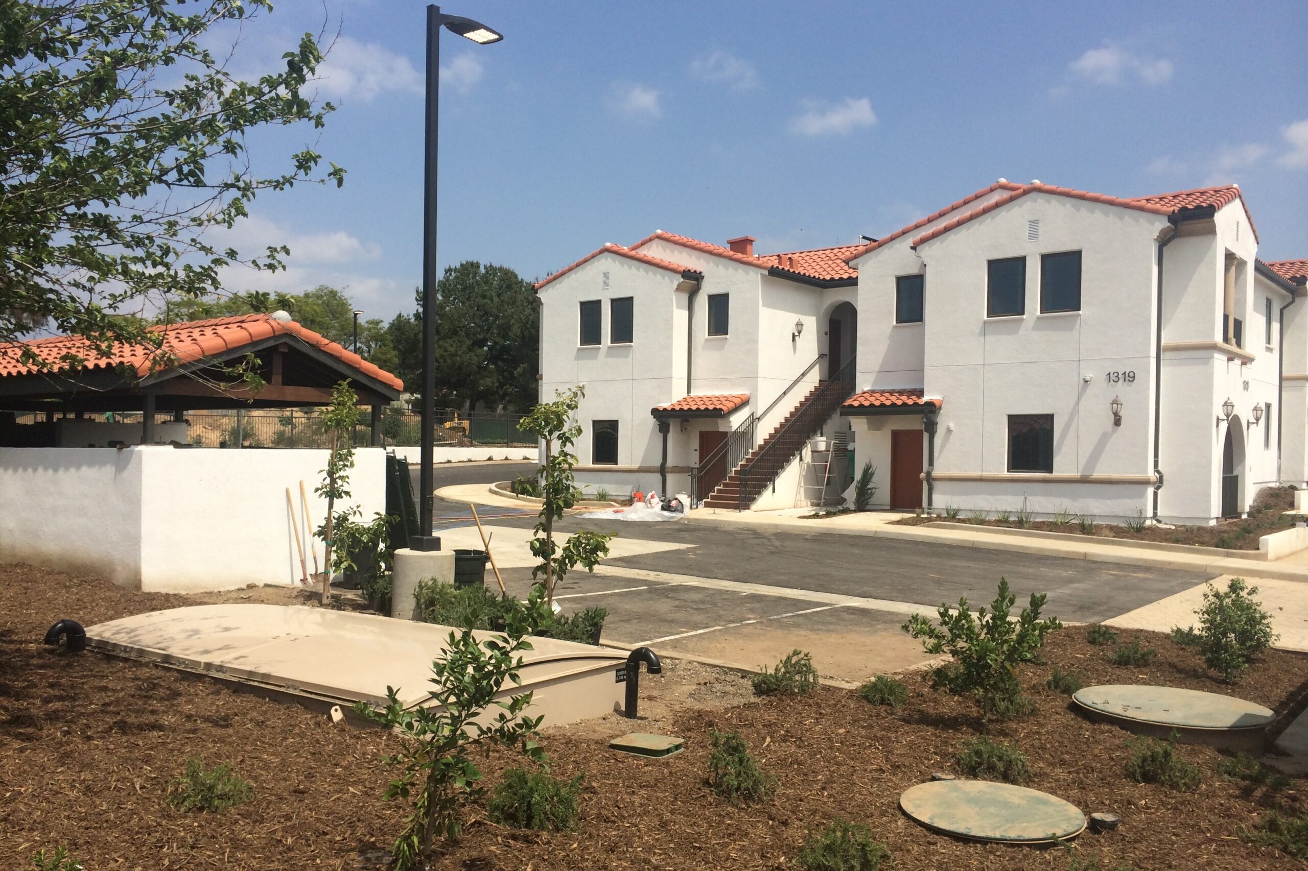 Affordable housing community with parking lot, light pole, and greywater system.
