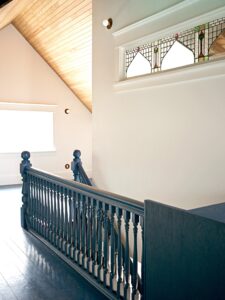 Interior of home with stairway rails, blue floor, dormered ceiling, and decorative glass clerestory - photo