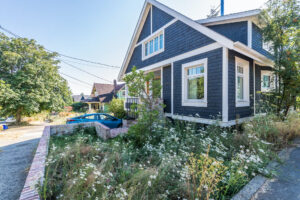 Blue house with white trim and abundant wildflower garden - photo