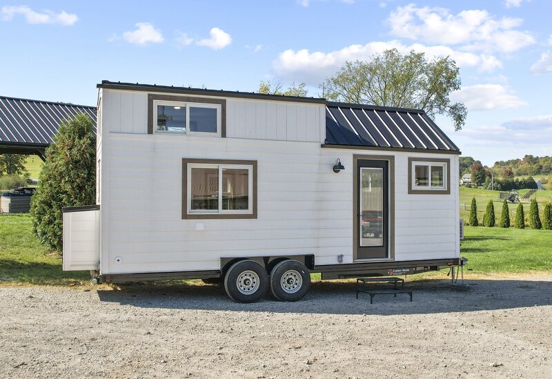 exterior view of modern tiny house on wheels in rural setting; white cladding, dark metal roof, and windowed sleeping loft - photo