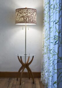 Interior of room with tall lighted lamp coming up though end table; patterned shade - photo