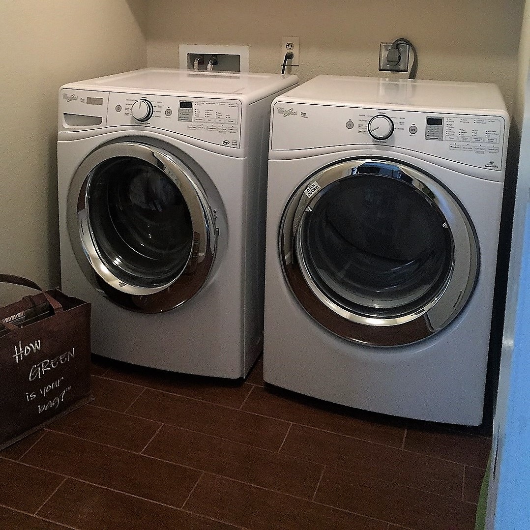ENERGY STAR washer and dryer dide-by-side in residential laundry room; tote bag sits on the tiled floor reads "How  green is your bag?" - photo