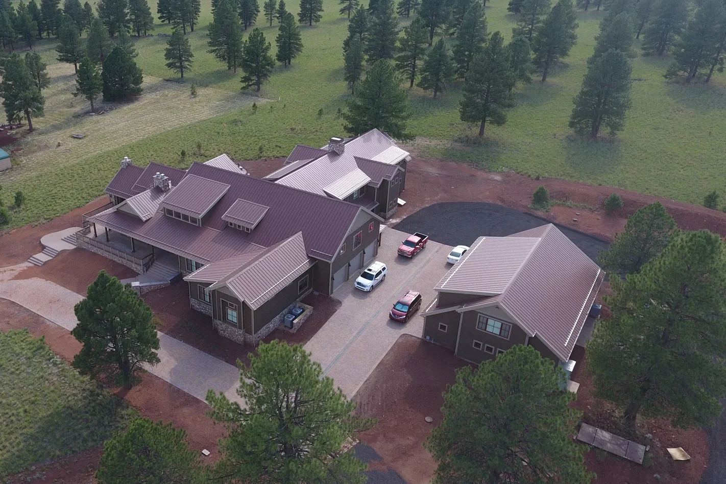 aerial view of sprawling home of SIP construction, surrounded by large outbuilding, fields and pines - photo