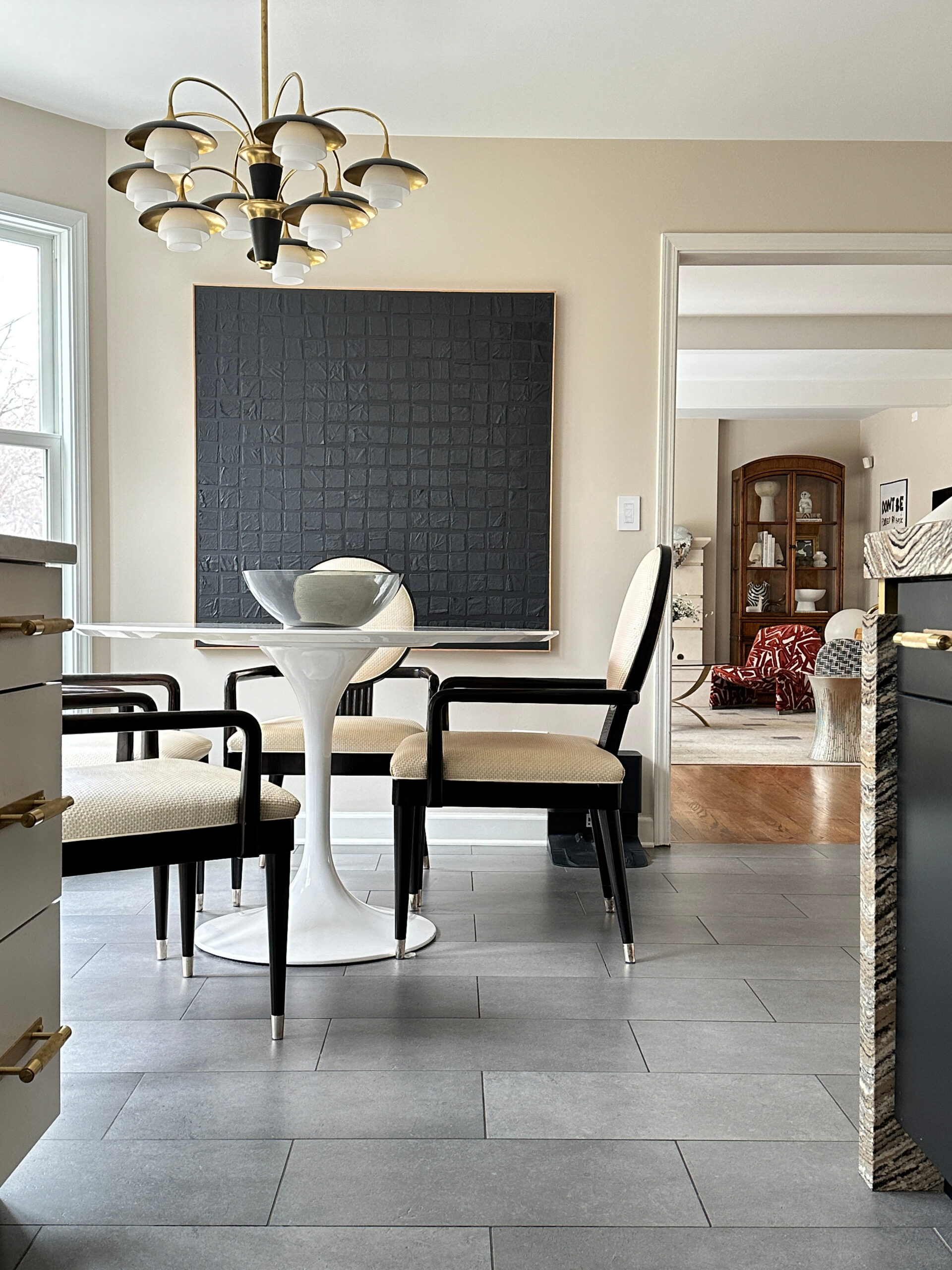 interior home, breakfast nook with modern table and brass-and-glass chandelier; bright window at left illuminates large black textured art piece (Kelly Caldwell) on the far wall - photo 