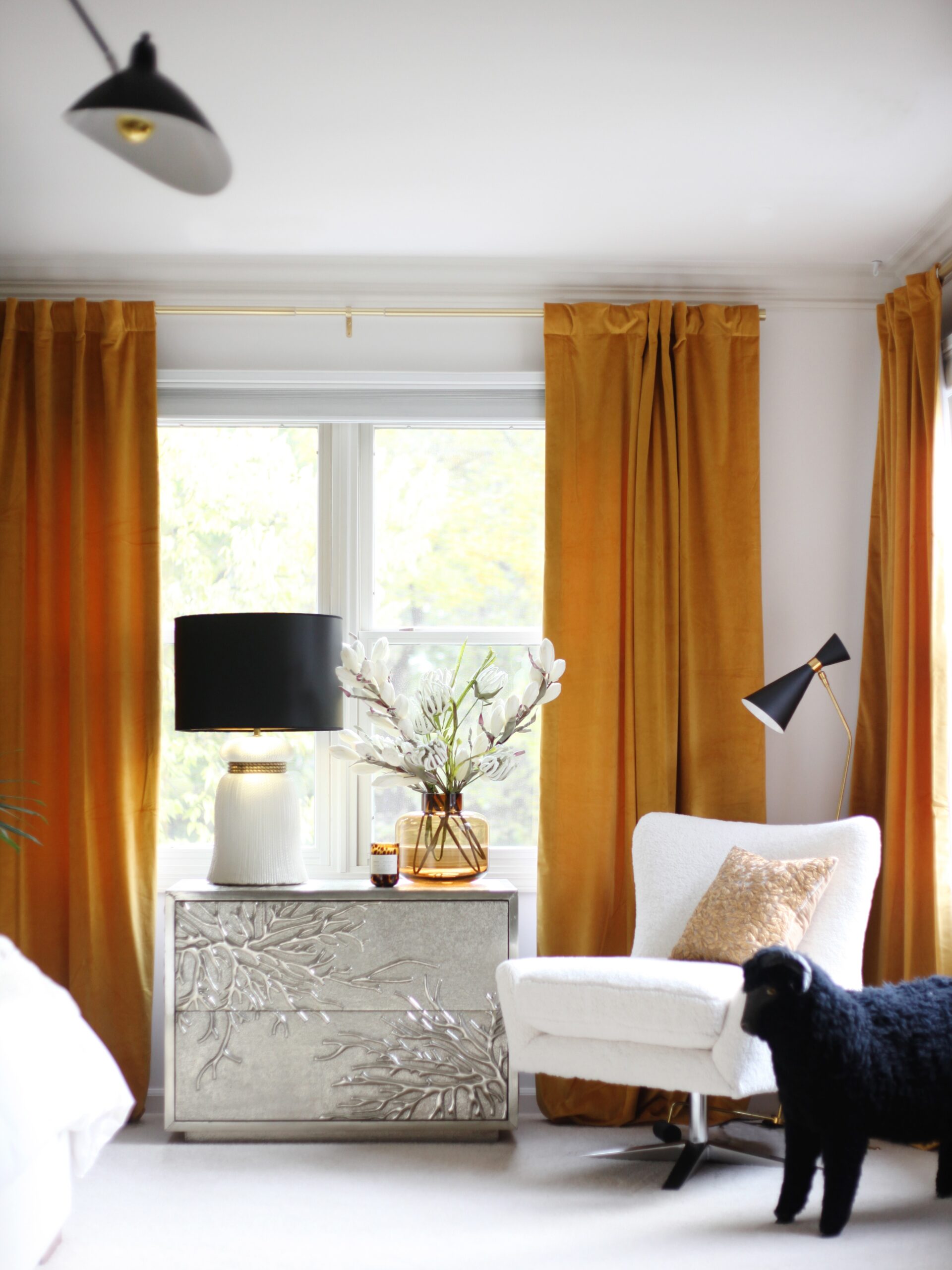 home interior bedroom; centerpiece is vintage furniture metal chest, stoneware lamp and black animal stuffie are accents - photo