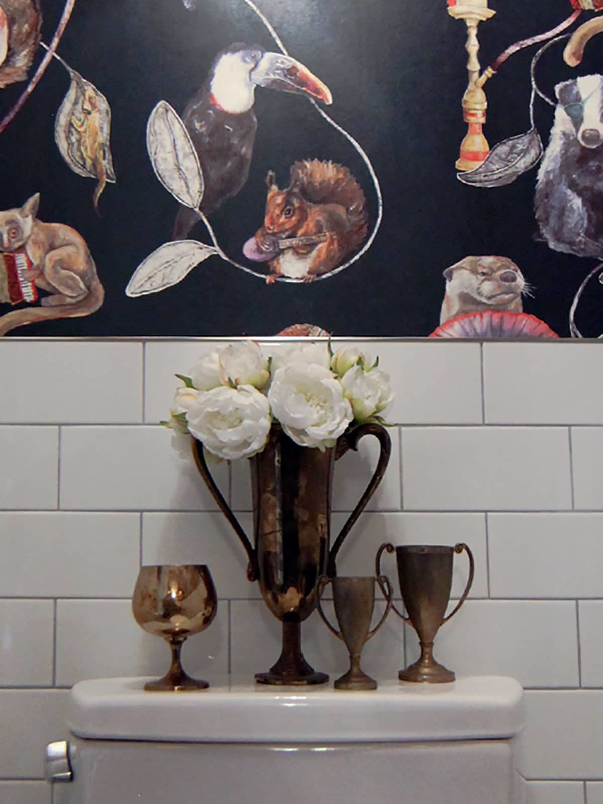 home interior bathroom, antique trophies, set off by white tile, hold flowers; striking wall paper features exotic animals - photo