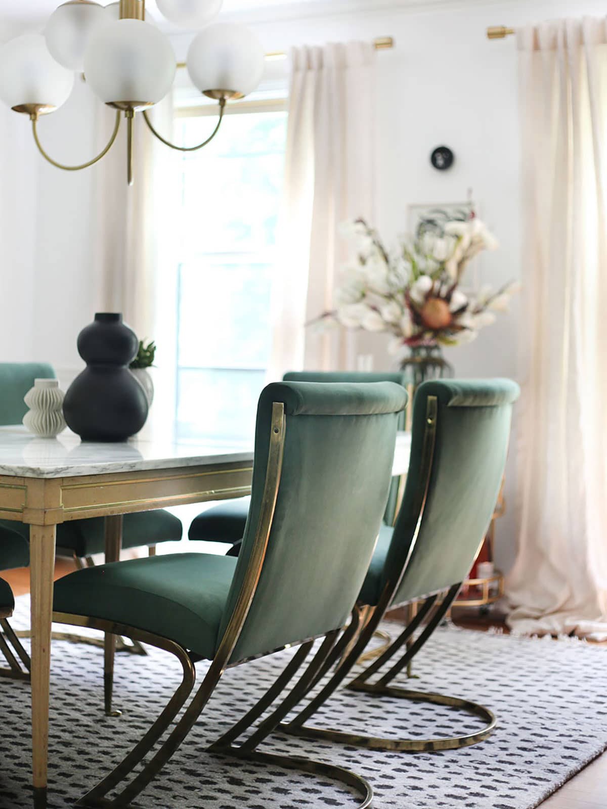 Home interior, modern green chairs at marble-topped dining table and chandelier large draped windows - photo